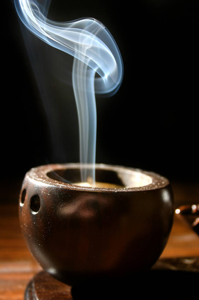 Una sottile scia di fumo sorge da un portacaffè marrone simile a un incenso - Foto, immagini