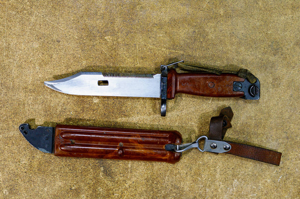 Штыковый нож из автомата Калашникова АК-47. Боевой нож на деревянном фоне. Военный символ армии. - Фото, изображение