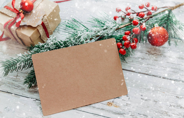Рождественские украшения, подарки с ремесленной открыткой для вставки текста на деревянный фон со снежинками. - Фото, изображение