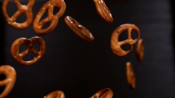 Salty pretzels fly up and hang in the air on a black background - Footage, Video