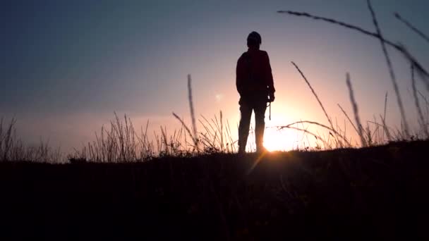 Miehen siluetti putoaa polvilleen pellolle auringonlaskun taustaa vasten - Materiaali, video