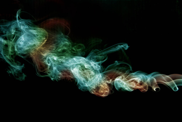 Green and orange smoke twisting on a black background - Photo, Image