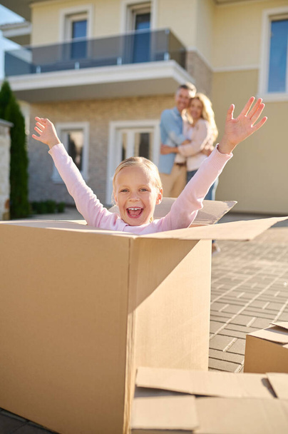Emotional girl with raised hands sitting in box - Photo, Image