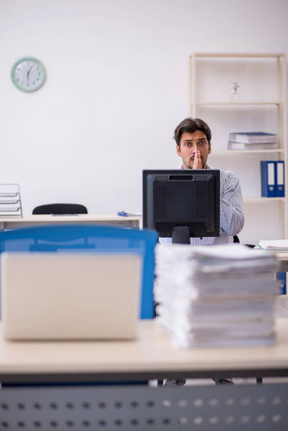 Молодой работник и слишком много работы в офисе - Фото, изображение