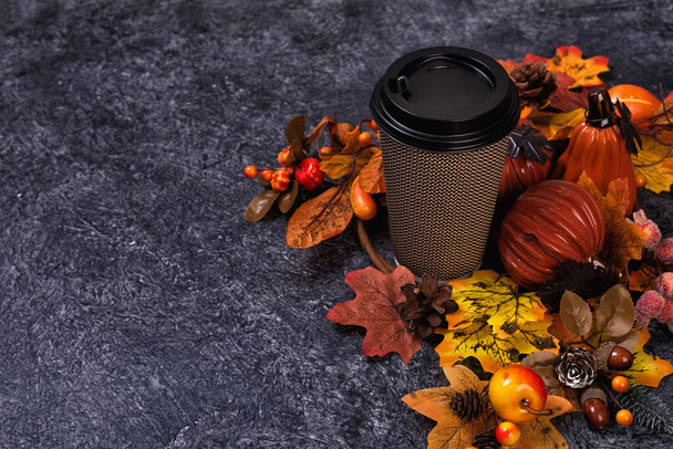 Paper cup of coffee or tea with autumn leaves and pumpkin decor - Photo, Image