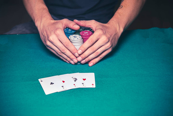Pokerde kazanan adam, masada 4 as ile yüklü miktarda para taşıyor. - Fotoğraf, Görsel