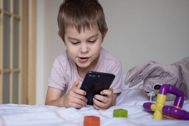 Little preschool boy playing via smartphone at home - Fotografie, Obrázek