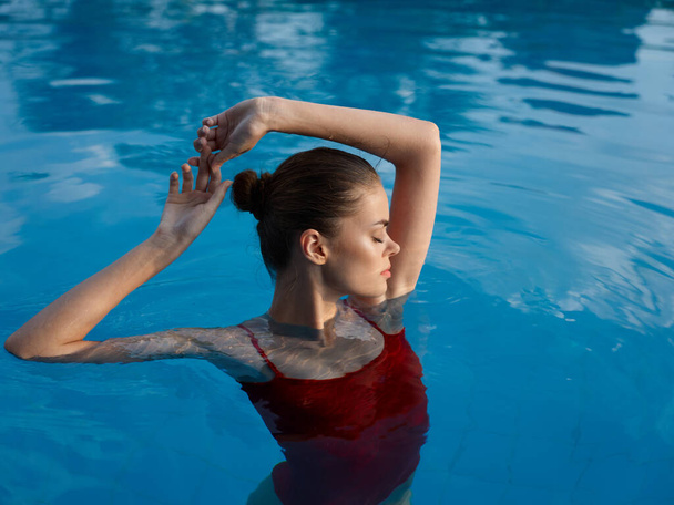 Frau im roten Badeanzug im Pool mit geschlossenen Augen, Handbewegungen - Foto, Bild