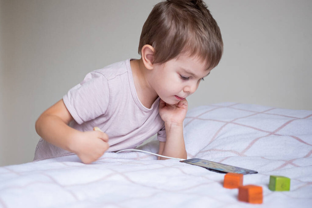 Little preschool boy playing via smartphone at home - Photo, image
