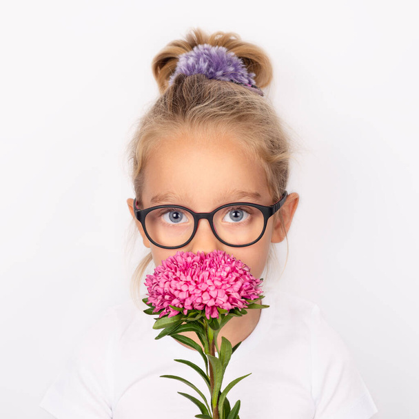 Gyermek lány kezében egy rózsaszín virág elszigetelt fehér háttérrel. Nemzetközi anyák napi koncepció - Fotó, kép