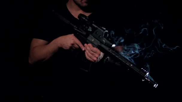 Um mercenário de uma empresa militar privada num fundo negro com um rifle táctico num kit de corpo tecnológico moderno - Filmagem, Vídeo