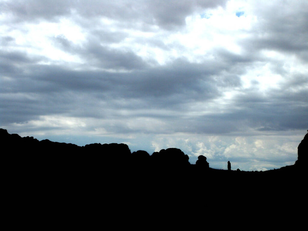 Suuret kivet siluetoituna harmaata ja pilvistä taivasta vasten auringon paistaessa läpi - Valokuva, kuva