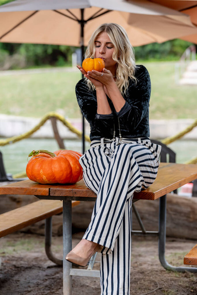 Ein hinreißendes blondes Model posiert während der Halloween-Feiertage in einem Kürbisfeld - Foto, Bild