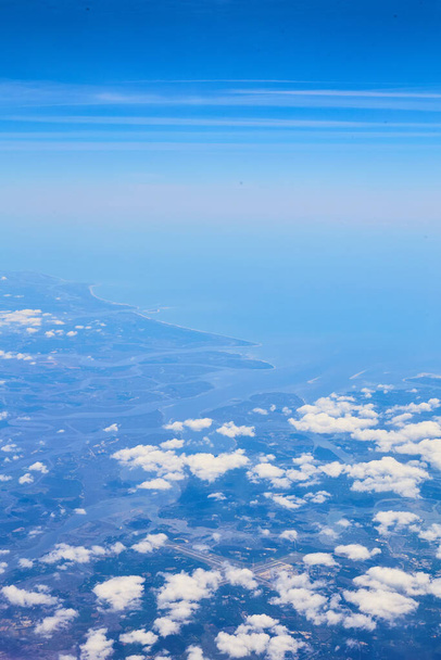 Αεροπλάνο άποψη των νεφών και μπλε του ουρανού με τη γη σε απόσταση - Φωτογραφία, εικόνα