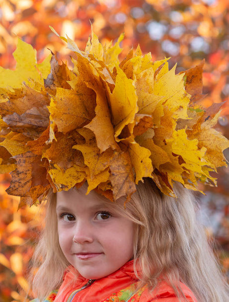 Jesienią. Portret dziewczyny z wieńcem żółtego upadłego klonu na głowie w jesiennych kolorach.  - Zdjęcie, obraz