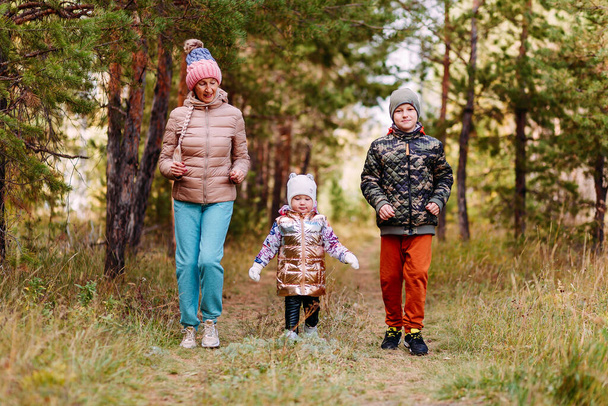 children and an elderly woman run along a path in the woods in the fall - Фото, зображення