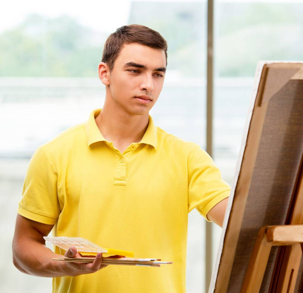 Young male artist drawing pictures in bright studio - Foto, afbeelding
