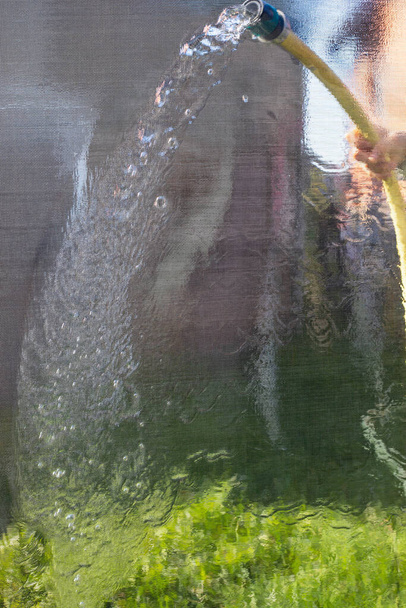 lavar mosquiteiros de uma mangueira com água close-up vertical - Foto, Imagem