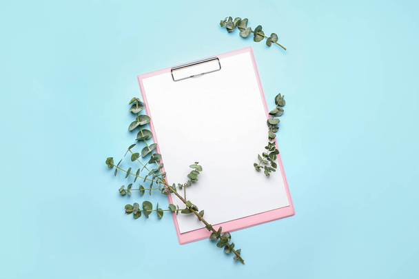 Clipboard with blank sheet of paper and fresh eucalyptus branches on color background - Zdjęcie, obraz