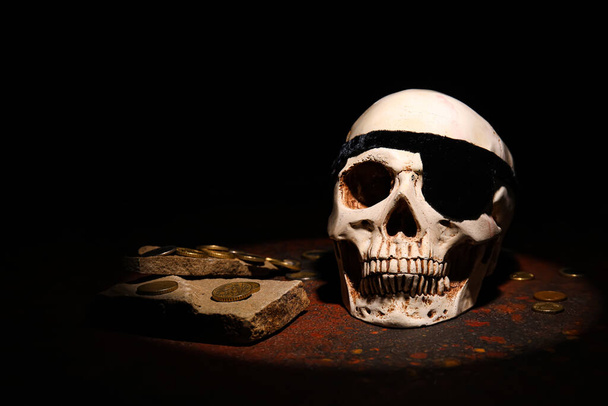 Pirate skull with golden coins on dark background - Photo, Image