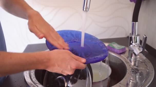 Muž myje nádobí houbou. Člověk umyje prací prášek vodou z nádobí. Detailní záběr ruky muže, který umývá nádobí. Ten chlap po sobě umývá nádobí. - Záběry, video