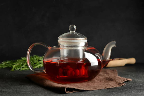 Theepot met heerlijke cranberry thee op donkere achtergrond - Foto, afbeelding