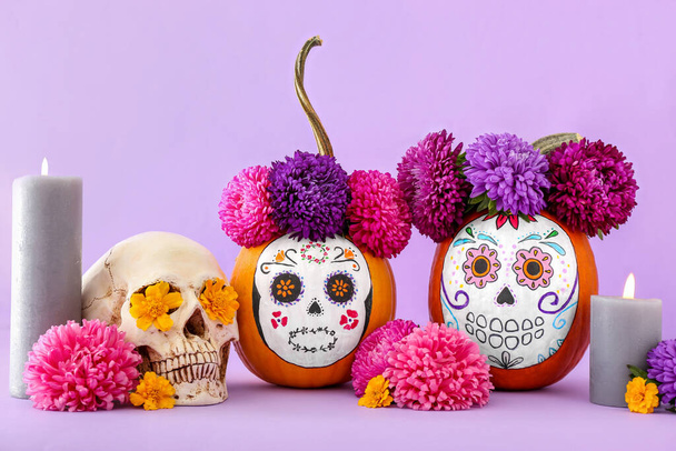 Kürbisse mit gemaltem Totenkopf auf farbigem Hintergrund. Feier des mexikanischen Tages der Toten (El Dia de Muertos)) - Foto, Bild