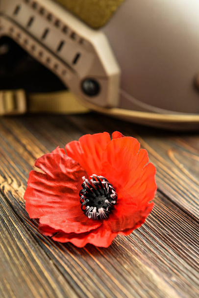 Poppy flower and helmet on wooden background. Remembrance Day - Photo, Image