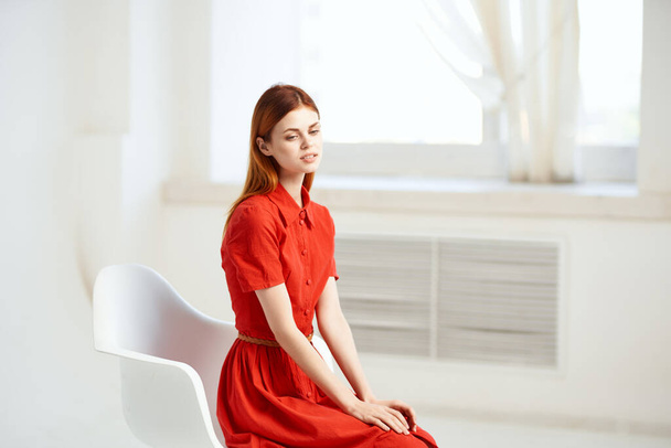 mulher sentada em uma cadeira vestido vermelho sala de pose - Foto, Imagem