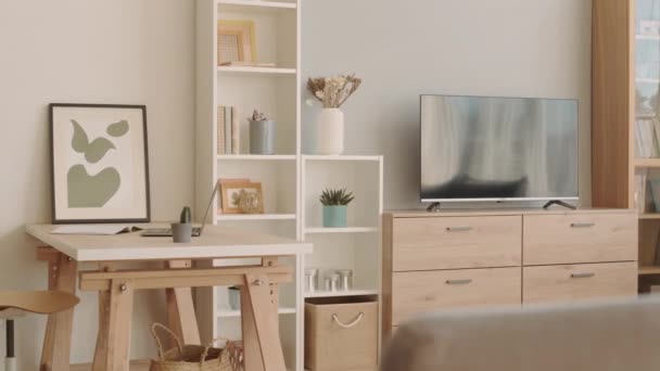 Brak osób przegląd przytulny minimalistyczny styl życia lub utrzymanie pokoju z telewizorem na drewnianym kredensie, stół, półki i biblioteczka ze szklanymi drzwiami - Materiał filmowy, wideo