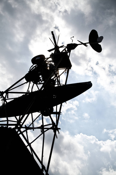Большая ветряная мельница силуэт против в основном облачное небо с солнечным светом подглядывая через - Фото, изображение