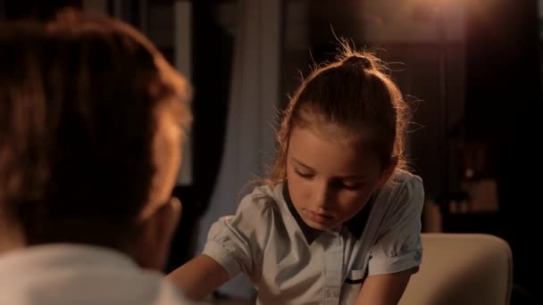Menina bonita nova da idade escolar joga um jogo concentrado de xadrez com um colega de classe. Cinemático - Filmagem, Vídeo