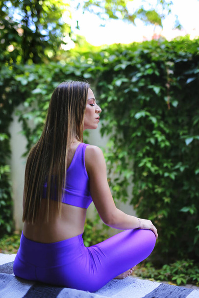 Chica atractiva practicando yoga en un exuberante jardín verde - Foto, imagen