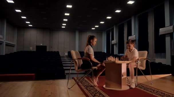 Genç bir kız, bir çocuk satranç yarışmasında akranını mat etmeye çalışıyor. - Video, Çekim