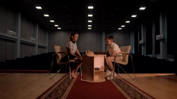 Alumnos niño y niña juegan al ajedrez en el salón de actos - Imágenes, Vídeo
