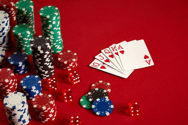 Équipement de poker de jeu de casino et concept de divertissement - gros plan des cartes à jouer et des jetons en arrière-plan rouge. Coeur Royal Flush. - Photo, image