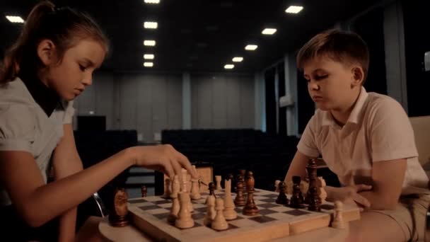 Ένα νεαρό όμορφο κορίτσι σε σχολική ηλικία κερδίζει στο σκάκι με τον συμμαθητή της. - Πλάνα, βίντεο