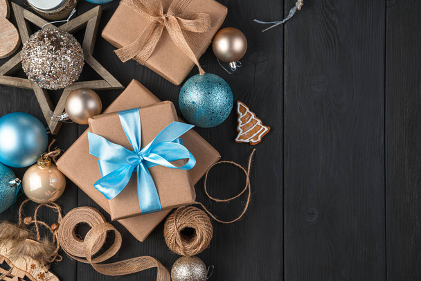Juguetes de Navidad y regalos con cintas azules sobre un fondo negro. Vista superior, espacio de copia. - Foto, Imagen
