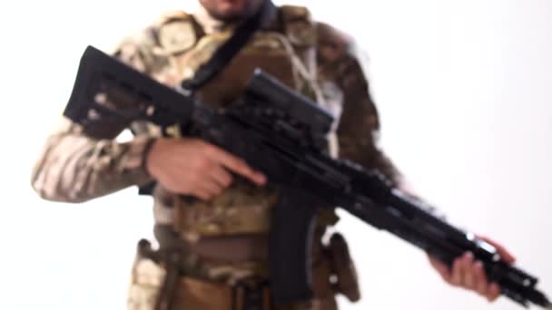 Egy katona modern katonai ruhában és testpáncélban, egy géppuskával a kezében belép a képbe a disszocustól. Fehér háttér. Elszigetelt. - Felvétel, videó