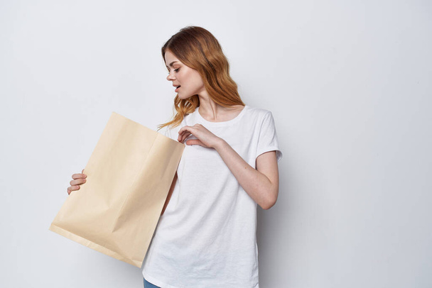 mujer en camiseta blanca paquete con compras fondo claro - Foto, imagen