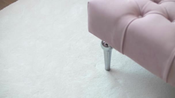 Fondo con una suave alfombra blanca y un puf rosa suave en una habitación moderna con un elegante diseño interior. Primer plano - Metraje, vídeo