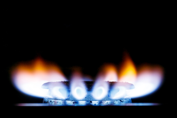 Silný žlutomodrý plamen plynového hořáku v kuchyňském sporáku ve tmě. Umístit pod text. - Fotografie, Obrázek