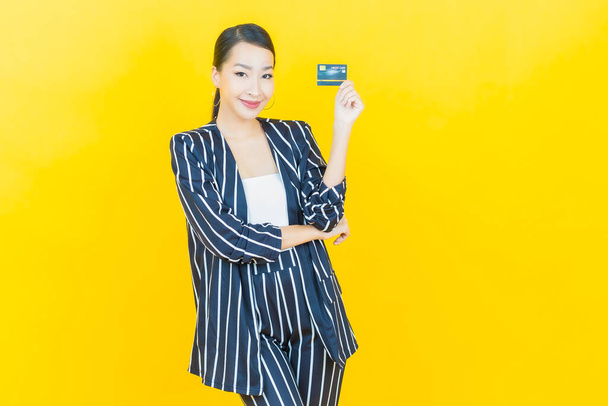 Retrato hermosa joven asiática mujer sonrisa con tarjeta de crédito en color de fondo - Foto, Imagen