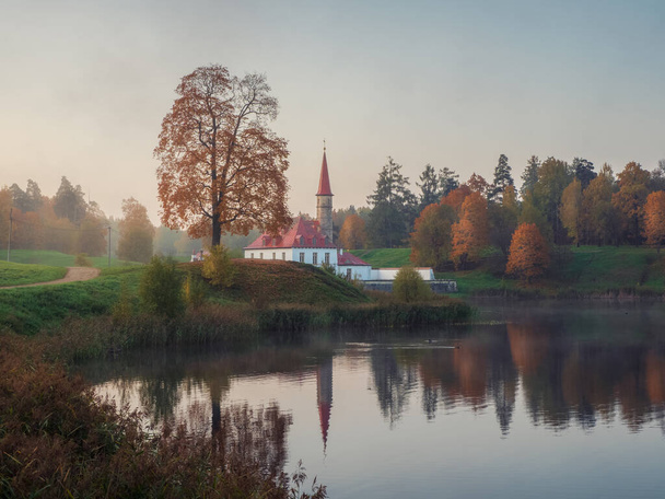 Soft focus. Sunny autumn morning landscape. A bright autumn misty landscape with golden trees by the pond and an old palace. Gatchina. Russia. - Fotografie, Obrázek