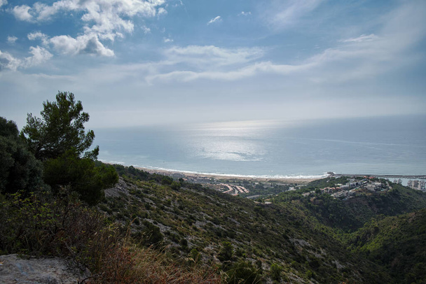 Paesaggio delle montagne rocciose del Parco Naturale Castelldefels e la sua spiaggia con il mare calmo e il cielo coperto di nuvole al mattino. - Foto, immagini