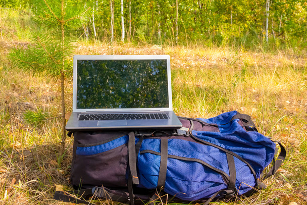ноутбук, стоящий на синий туристический рюкзак, природа, удаленная работа, - Фото, изображение
