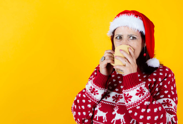 Older woman laying down with a traditional Christmas mug. santa claus hat - 写真・画像