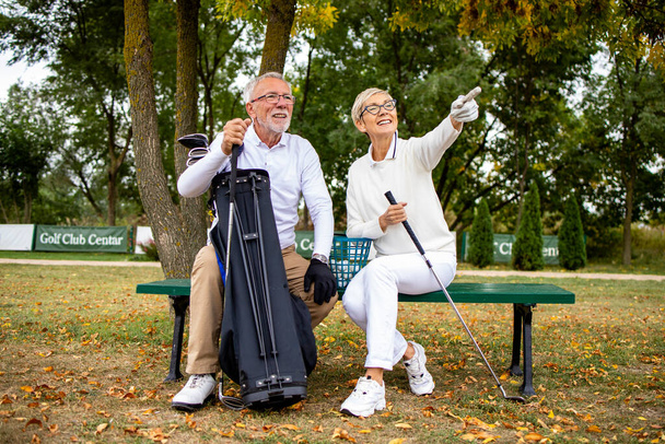 ゴルフ場での笑顔のシニアカップルの肖像ゲームトーナメントを見て楽しむ. - 写真・画像