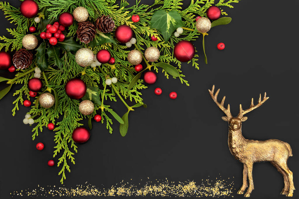 トナカイ、赤と金の泡の装飾、冬の緑、緩やかなホリーベリーとクリスマスの背景。ソルスティス、新年の休日の季節のための祭りのシーン。灰色の背景で。トップ表示コピースペース.   - 写真・画像