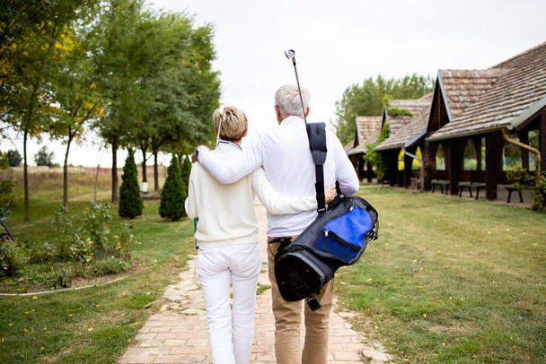 Couple de personnes âgées se tenant ensemble et profiter du temps de loisirs à la retraite en jouant au golf. - Photo, image